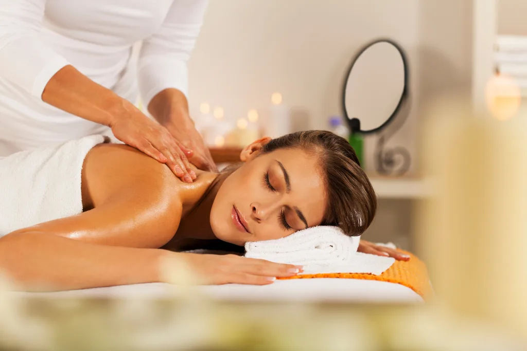Experience a luxurious massage at Spa Restoration Center, a premier luxury spa in Arlington, VA. A woman with closed eyes enjoys a relaxing shoulder massage in a softly lit, upscale spa environment.
