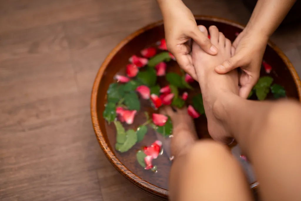 Pampering foot treatment at Spa restoration center, featuring a floral foot soak and massage, both contributing to overall foot health and well-being.