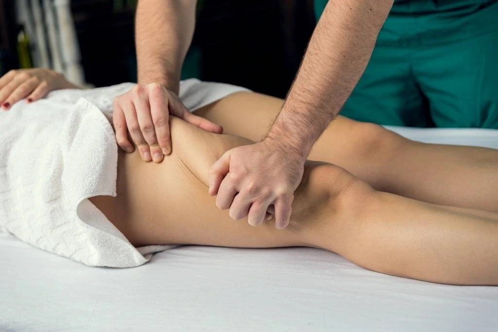 A person receives a thigh massage at Spa Restoration Center, showcasing lymphatic drainage techniques that can lead to healthier, glowing skin.