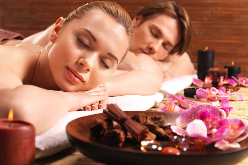 Relaxed couple enjoying a massage at Spa Restoration Center in Arlington, with orchids and candles.